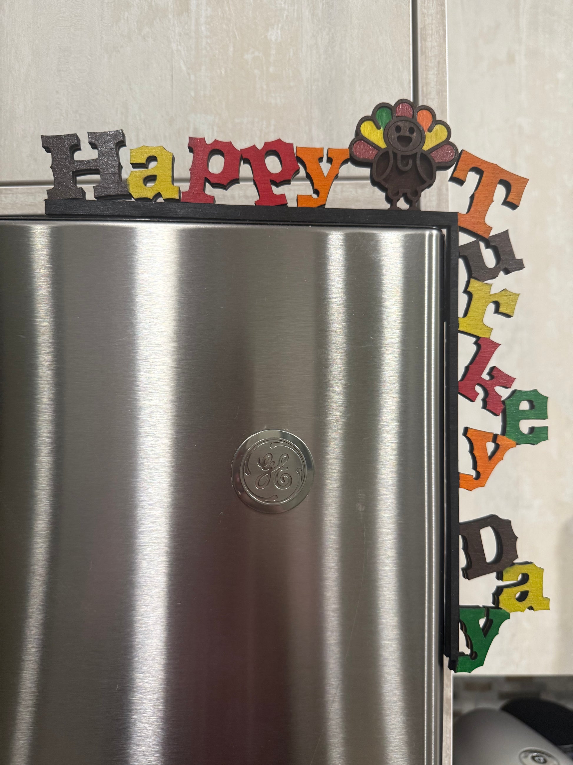 Decorative door decor spelling 'Happy Turkey Day' on a refrigerator.