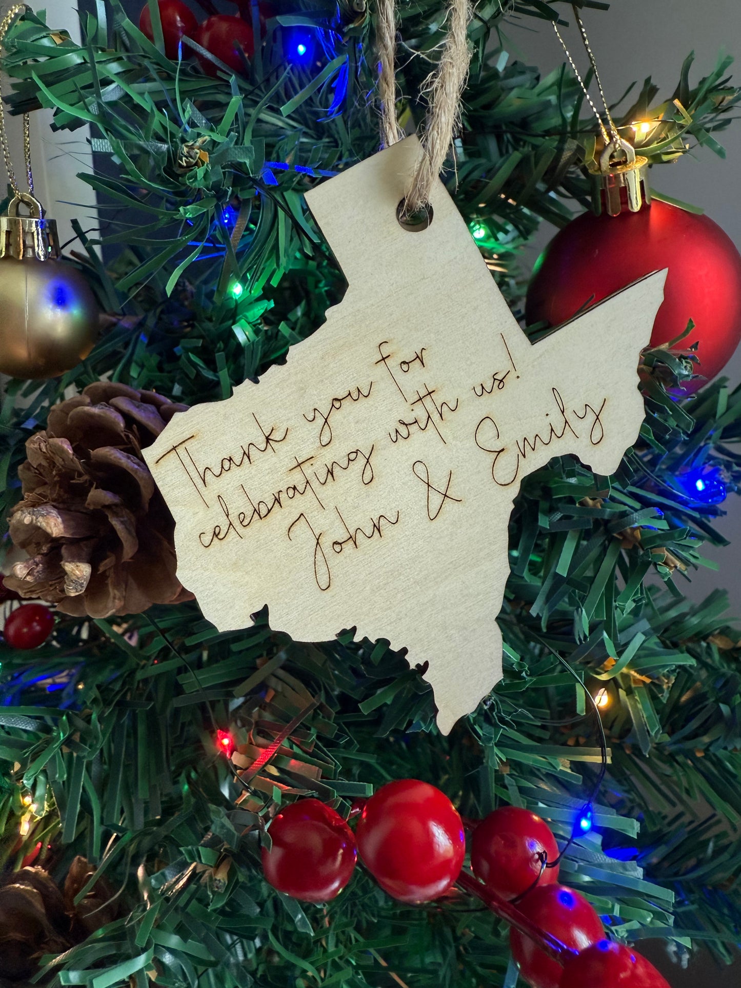 Christmas ornament with a tag reading 'Thank you for celebrating with us! John & Emily' on a decorated tree.
