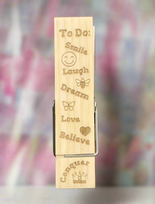 Wooden clip with motivational phrases and symbols on a blurred background